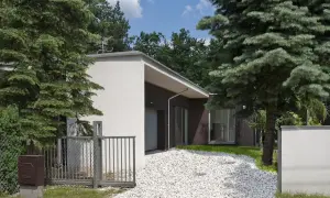 Nowoczesny dom z białym podjazdem z kruszywa, otoczony zielenią. Inspiracje dla Twojego ogrodu.