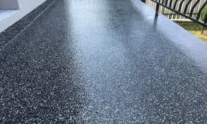 Nowy, błyszczący balkon z żywicą epoksydową w ciemnym kolorze z białymi płatkami. Wygląda nowocześnie i jest łatwy w utrzymaniu.