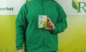 Kobieta w zielonej bluzie trzyma opakowanie stymulatora wzrostu roślin. Na opakowaniu widnieje napis "SUMIN ASAMI SL", a pod nim "STYMULUJE WZROST I PLONOWANIE ROŚLIN". Informacje o dawkowaniu są widoczne na dole.