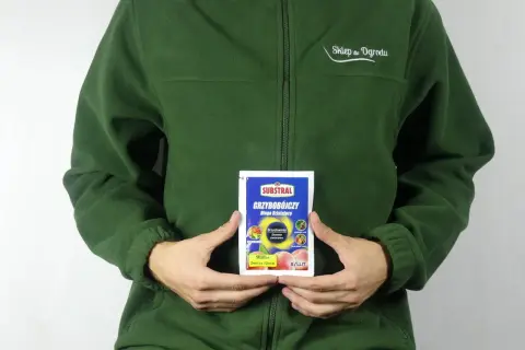 Osoba w zielonej bluzie trzyma opakowanie środka grzybobójczego SYLLIT 65 WP. Produkt przeznaczony jest do ochrony drzew owocowych.