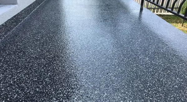 Nowy, błyszczący balkon z żywicą epoksydową w ciemnym kolorze z białymi płatkami. Wygląda nowocześnie i jest łatwy w utrzymaniu.