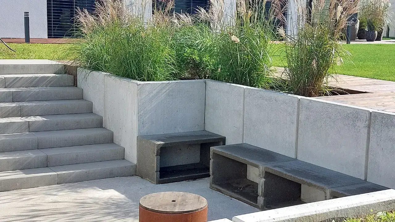 Nowoczesny ogr&oacute;d z betonowym murem, schodami i siedziskami. Zastanawiasz się, czym obłożyć murek betonowy? Tutaj beton stanowi gł&oacute;wny materiał.